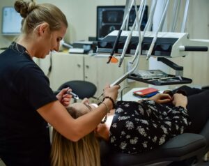 Professionnel dentaire effectuant un examen avec un équipement de pointe dans une clinique moderne, assurant le confort du patient.