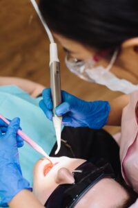Un dentiste effectue une intervention à l'aide d'un équipement dentaire moderne sur un patient portant des lunettes de protection.