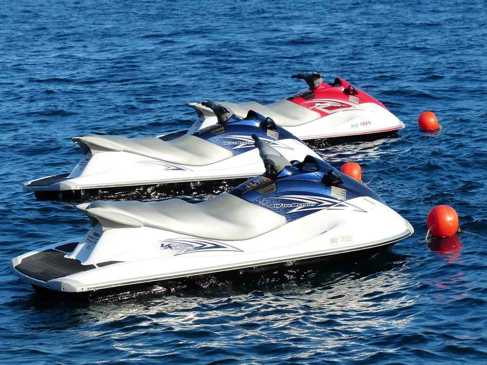 Trois jet-skis blancs et rouges amarrés côte à côte sur l'eau Trois jet-skis blancs et rouges amarrés côte à côte sur l'eau