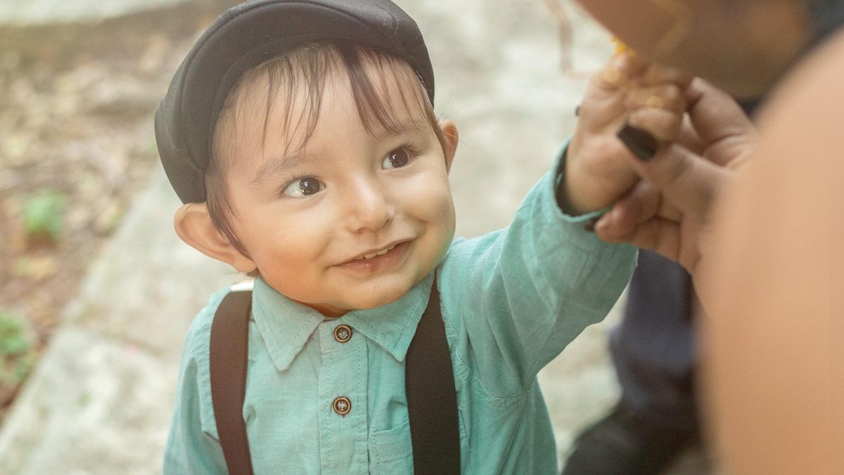 Petit garçon souriant lève la main pour toucher quelque chose