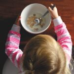 Une petite fille en pyjama rose mange des céréales au petit déjeuner