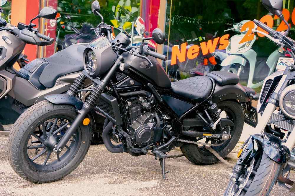 Moto noire et deux autres motos devant une vitrine de showroom