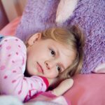 Fille couchée avec un grand nounours violet